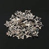 A pile of silver star-shaped metal snap hair clips scattered on a dark surface.