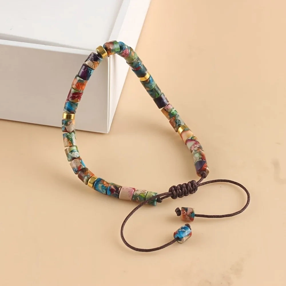 A friendship bracelet made of colorful natural stones with gold accents, displayed on a light background.