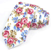 Une pile de nœuds papillons en coton à motifs floraux élégants, avec des roses roses, bleues et vertes sur fond blanc.