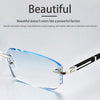 A pair of clear, frameless reading glasses with silver and black accents resting on a light gray surface.