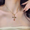 A close-up of a colorful zircon cross pendant necklace worn around the neck against a light skin tone.