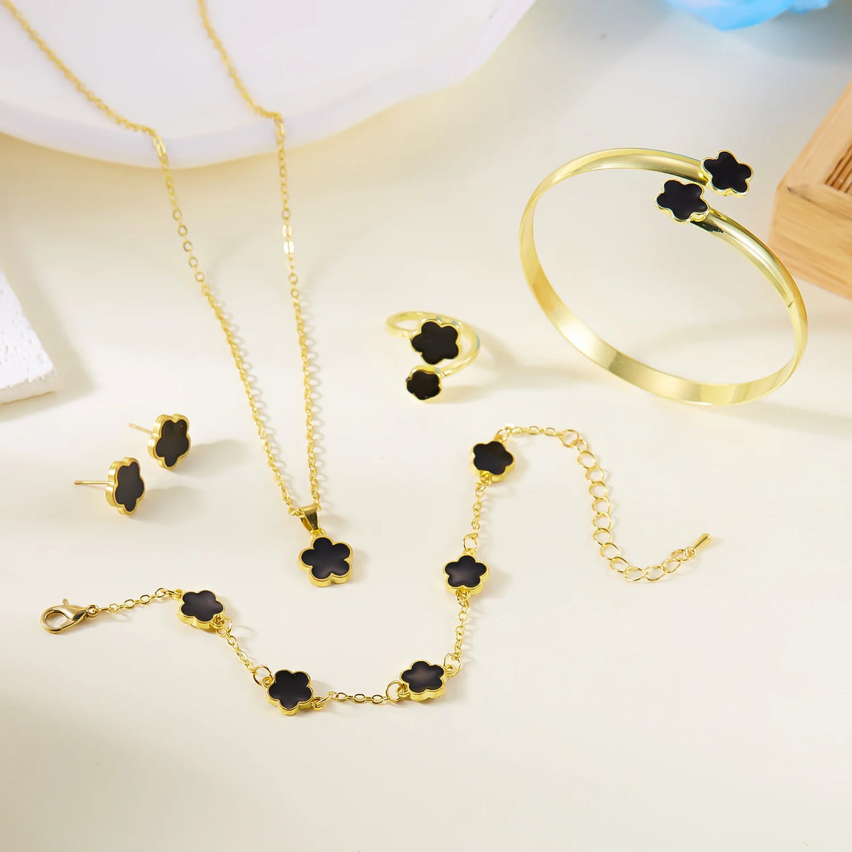 A set of five gold-colored bracelets and necklaces featuring black enamel plum blossoms.