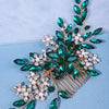 A sparkling green crystal and pearl hair comb accessory with leafy accents on a light blue background.
