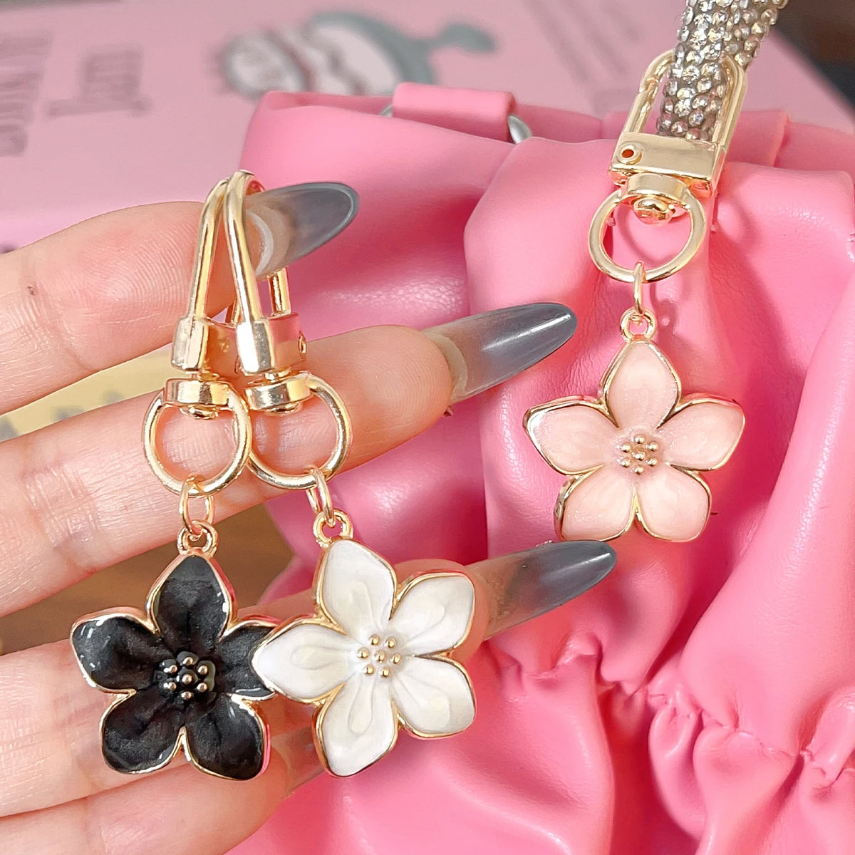 Llavero floral dorado con fondo de tela rosa sostenido por una mano.