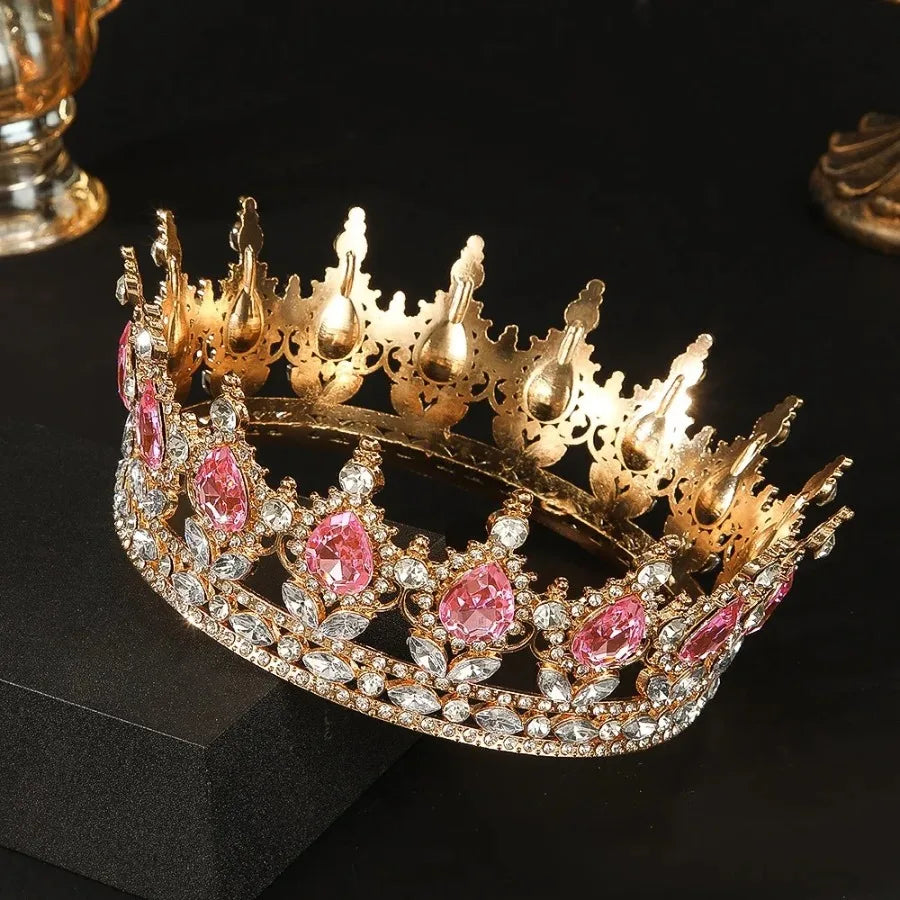 Couronne diadème en strass de cristal or et rose sur une surface sombre.