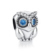 A silver owl charm featuring blue eyes and a crown of clear diamonds.