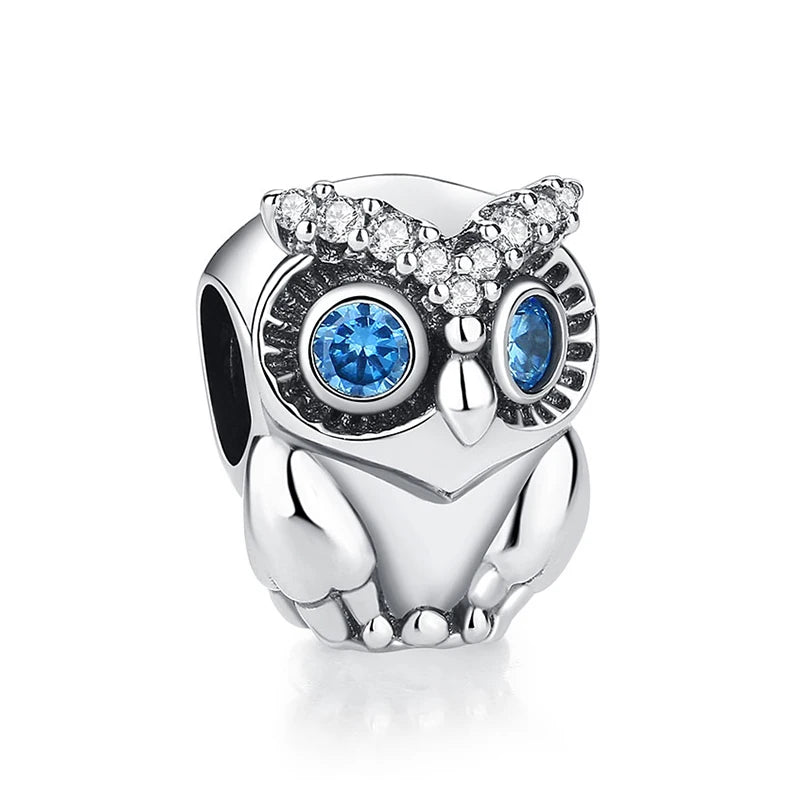 A silver owl charm featuring blue eyes and a crown of clear diamonds.