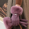 A close-up of plush purple wrist gloves with faux fur accents being held by a person wearing a brown coat.