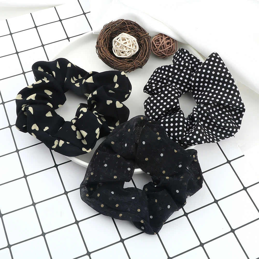 A set of three black knitted hair scrunchie headbands with various patterns and textures arranged on a white surface.