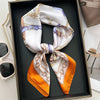 A silk scarf tied in a bow, featuring white and purple patterns, displayed in a dark tray.