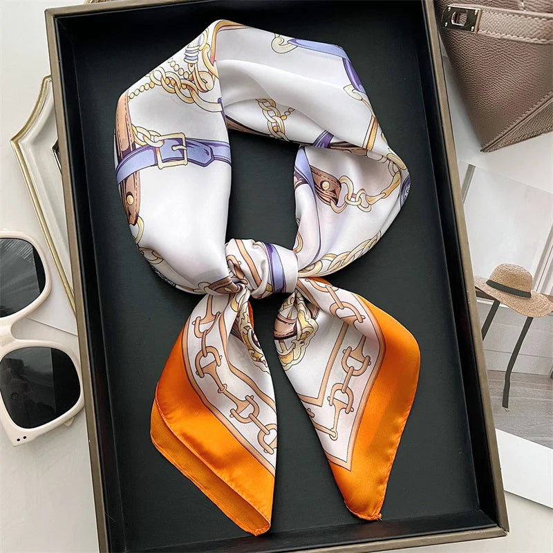 A silk scarf tied in a bow, featuring white and purple patterns, displayed in a dark tray.