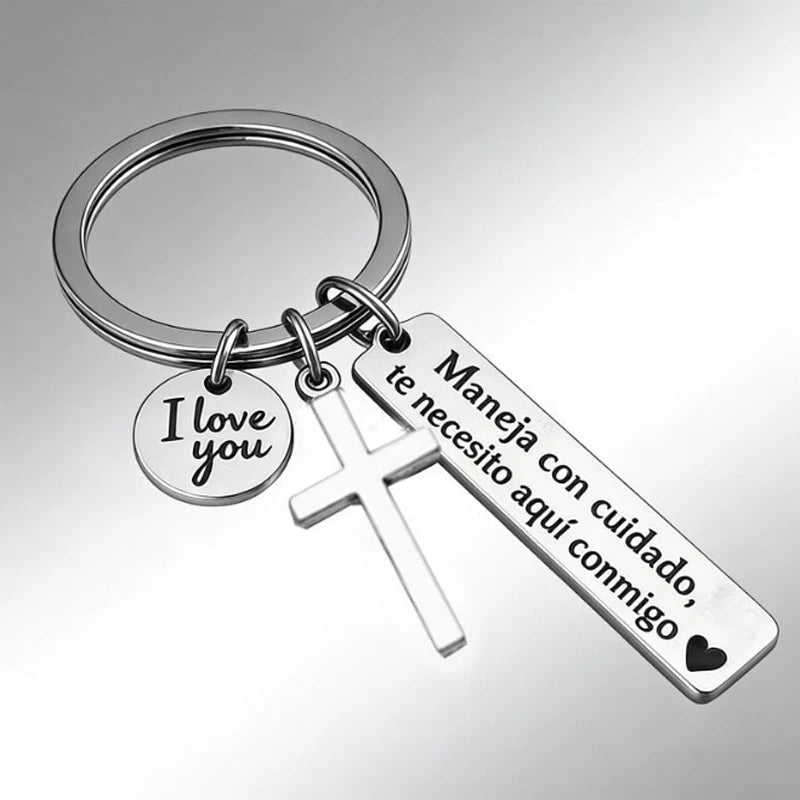 A silver stainless steel couple keychain featuring a heart charm and a tag with Spanish text.