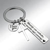 A silver stainless steel couple keychain featuring a heart charm and a tag with Spanish text.