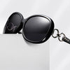Eine schwarze, polarisierte Sonnenbrille liegt auf einer weißen Box mit Text, der klassische und trendige Looks bewirbt.