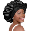 A woman wearing a black satin sleeping bonnet with an adjustable tie band.