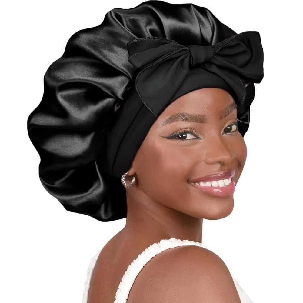 A woman wearing a black satin sleeping bonnet with an adjustable tie band.