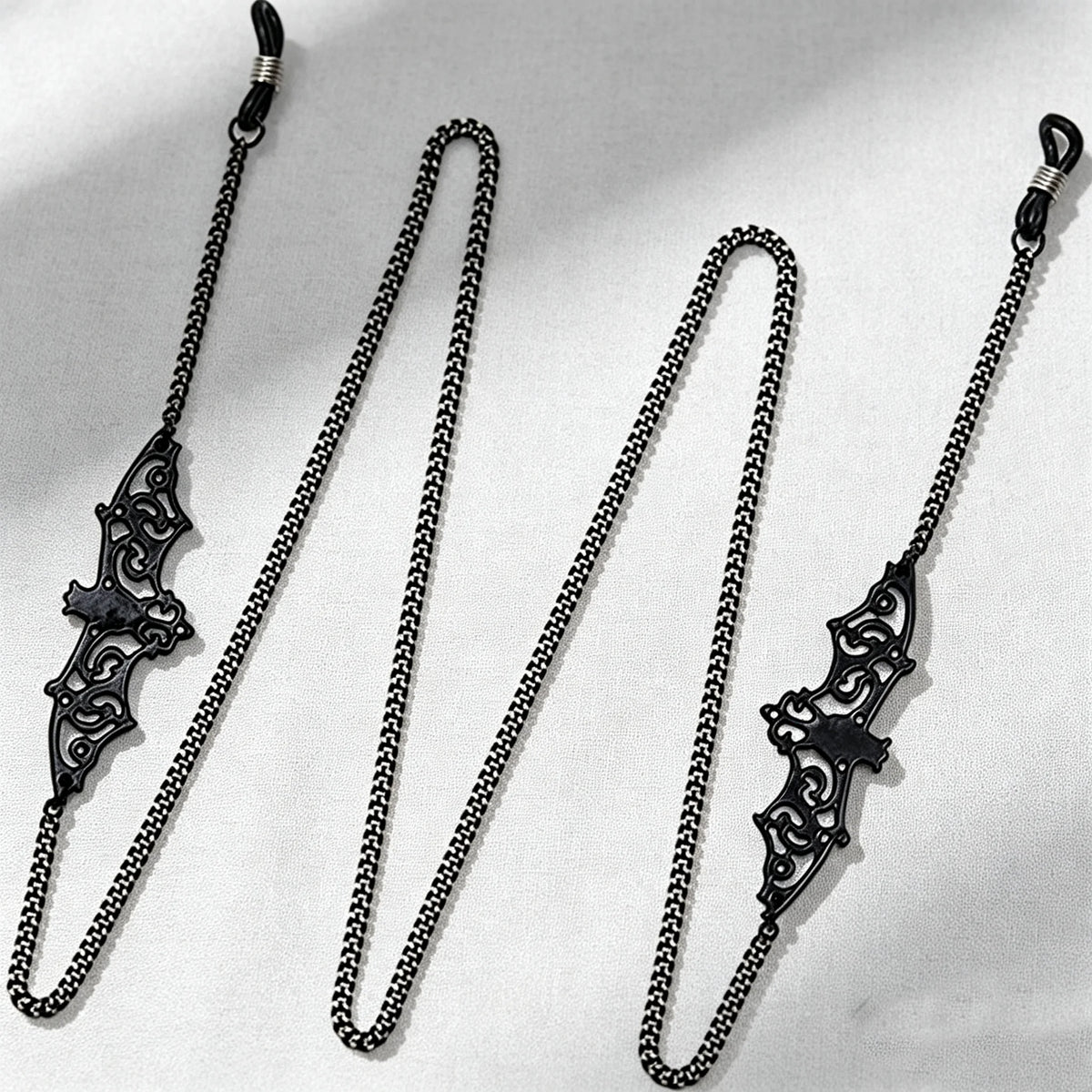 A set of black metal link eyeglass straps with decorative clasps displayed against a white background.