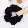 A black velvet scrunchie is shown next to a ruler for scale.
