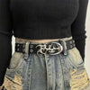 A close-up of a person wearing a black turtleneck and distressed denim jeans with a silver Y2K hollow PU leather fashion belt