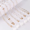 Gold-toned pearl and white bead necklace chains displayed on a white surface.