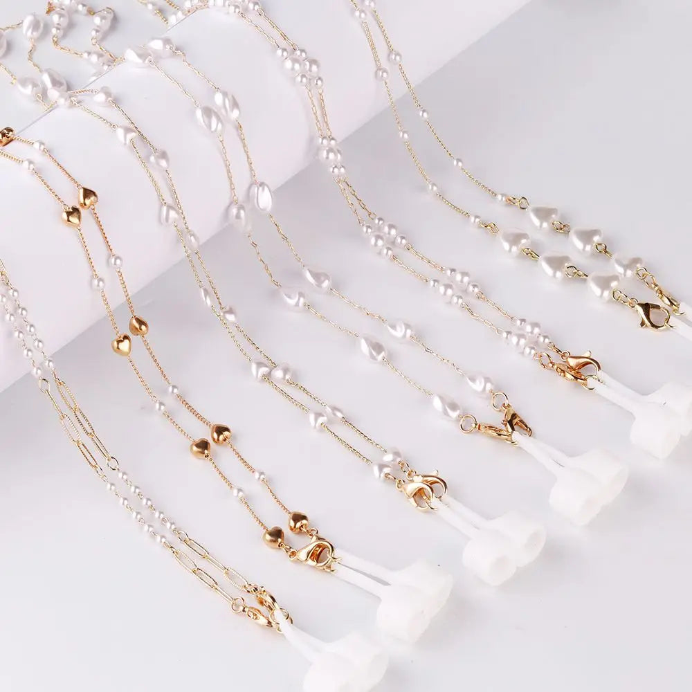 Gold-toned pearl and white bead necklace chains displayed on a white surface.