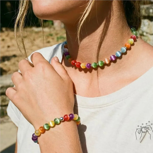 A close-up of a woman wearing a colorful beaded choker and bracelet set against a white shirt.