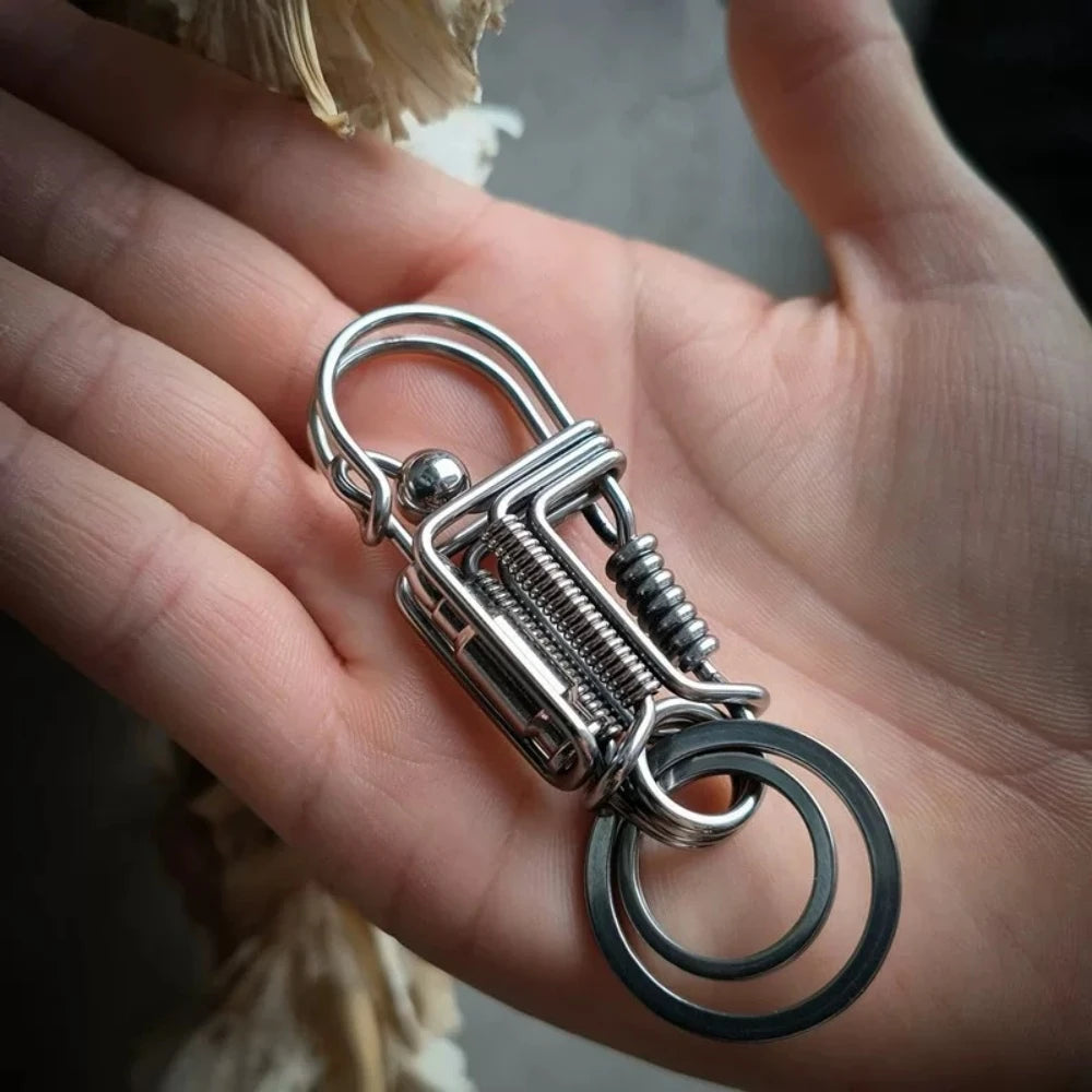 Une main tient un porte-clés mécanique en acier inoxydable avec un anneau circulaire et un anneau divisé.