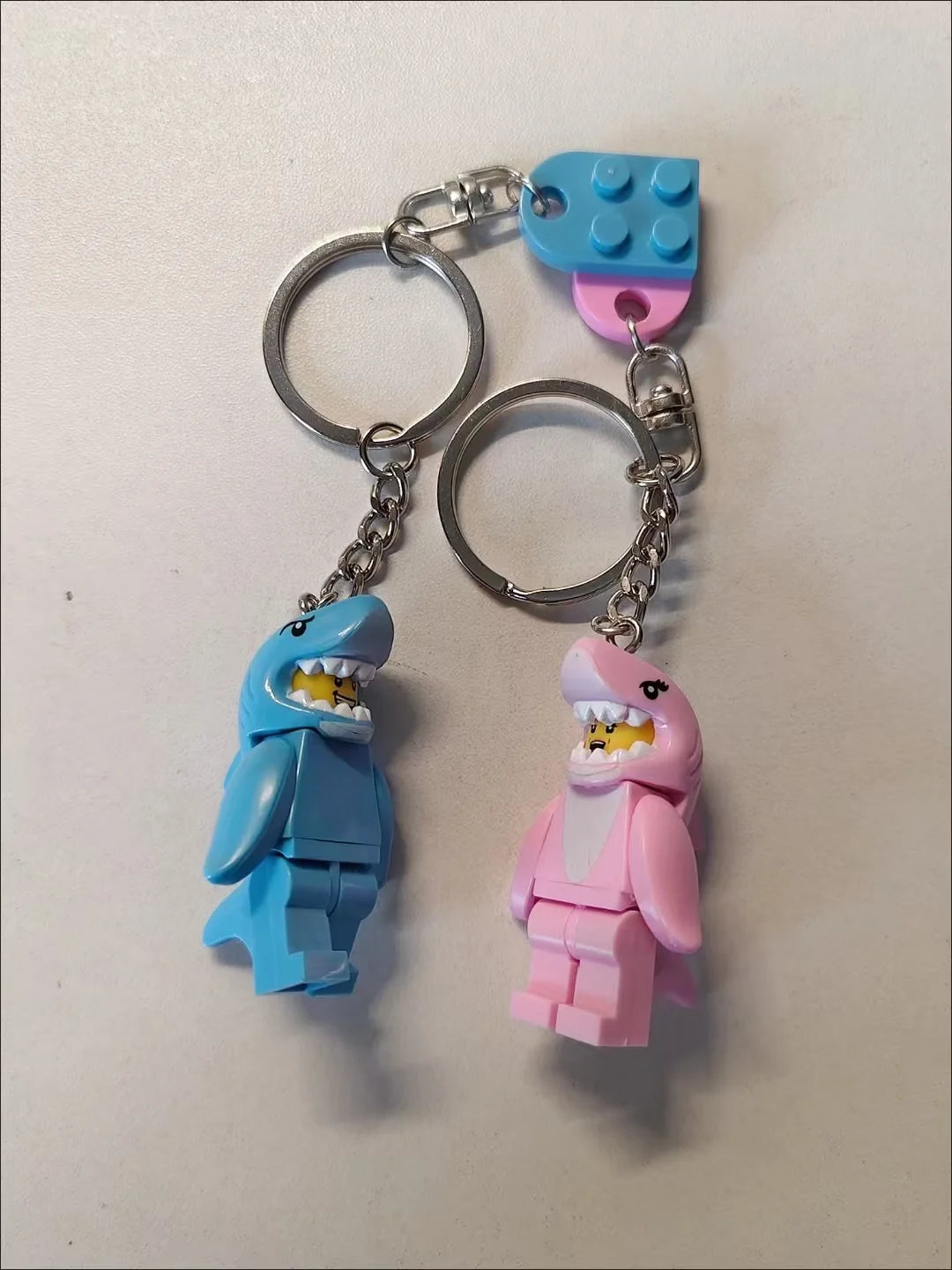 A set of heart-shaped building blocks in blue and pink, attached to metal split rings for a keychain.