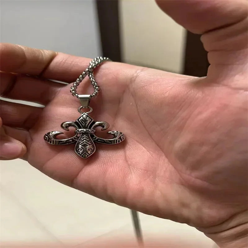 يد تحمل قلادة صليب فضية عتيقة بسلسلة وتصميم مزخرف.