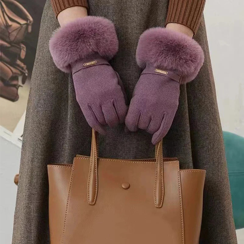 Lila Kunstfell-Handschuhe, die von einer Person gehalten werden, präsentiert vor einem braunen Mantel und einer braunen Leder