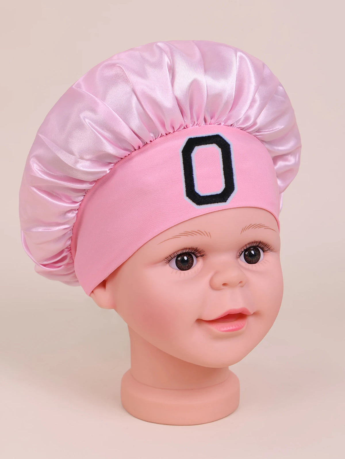Pink A-Z letter sleep cap for kids with a satin toque and a black letter O