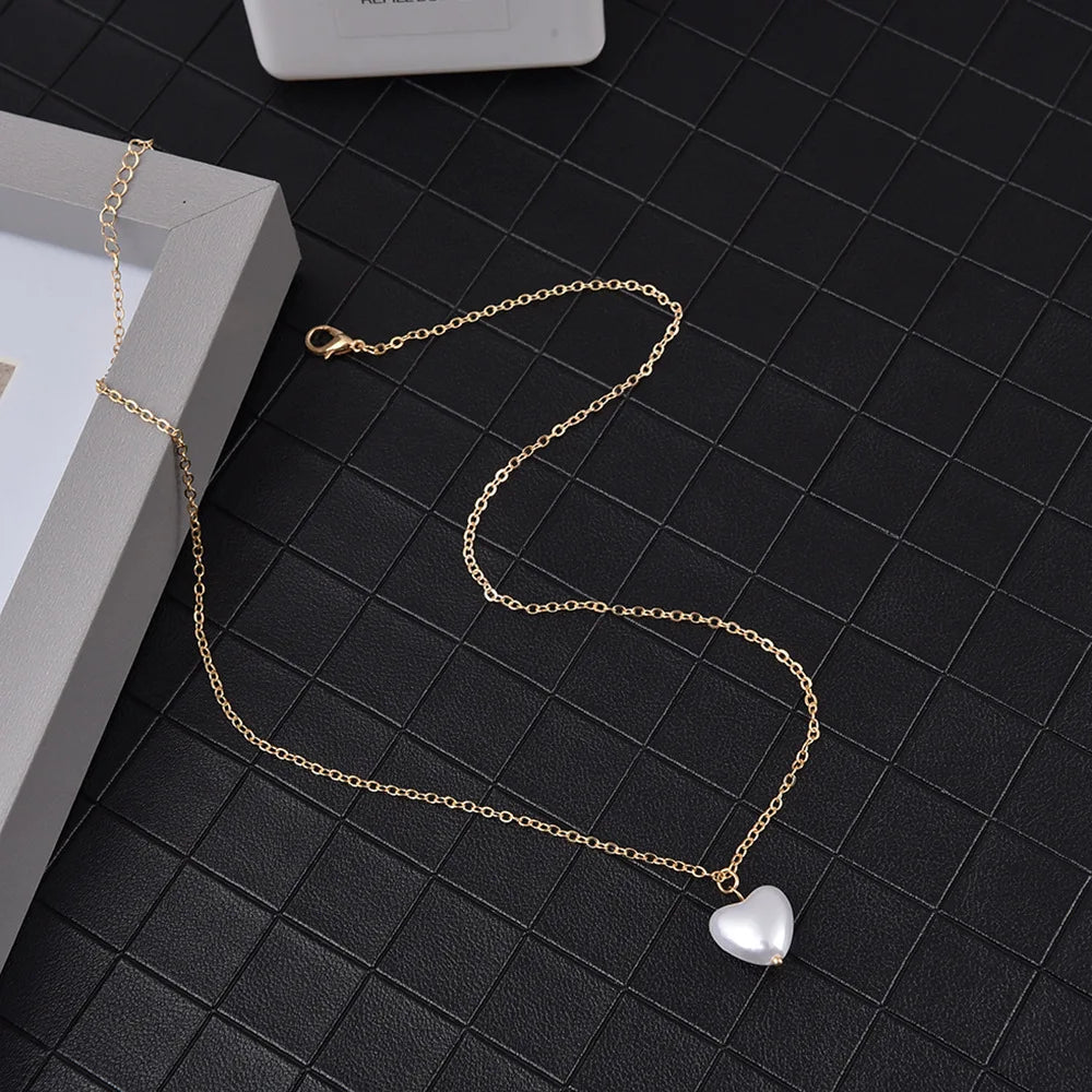 Gold chain necklace with a heart pendant displayed on a dark surface.