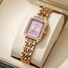 A gold-toned quartz wristwatch with a purple square face and rhinestone accents displayed in a light box.