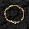A gold-colored stainless steel twisted chain bracelet laid on a dark, textured surface.