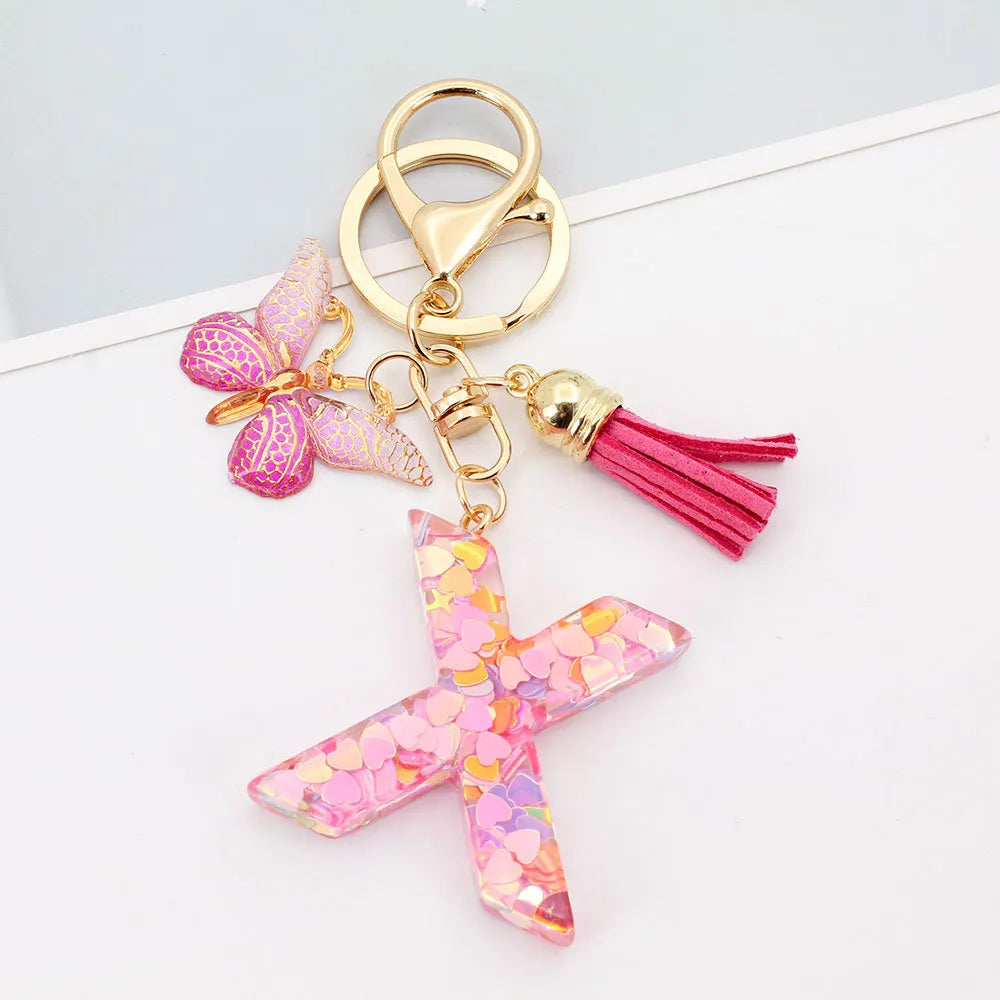Gold acrylic letter keychain featuring a pink butterfly charm and a magenta tassel