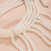 A set of imitation pearl statement necklaces draped on a light pink fabric.