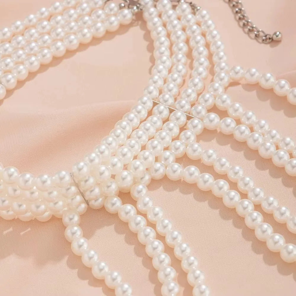 A set of imitation pearl statement necklaces draped on a light pink fabric.