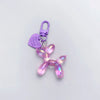 A pink resin animal dog keychain with a purple clasp and a heart tag.