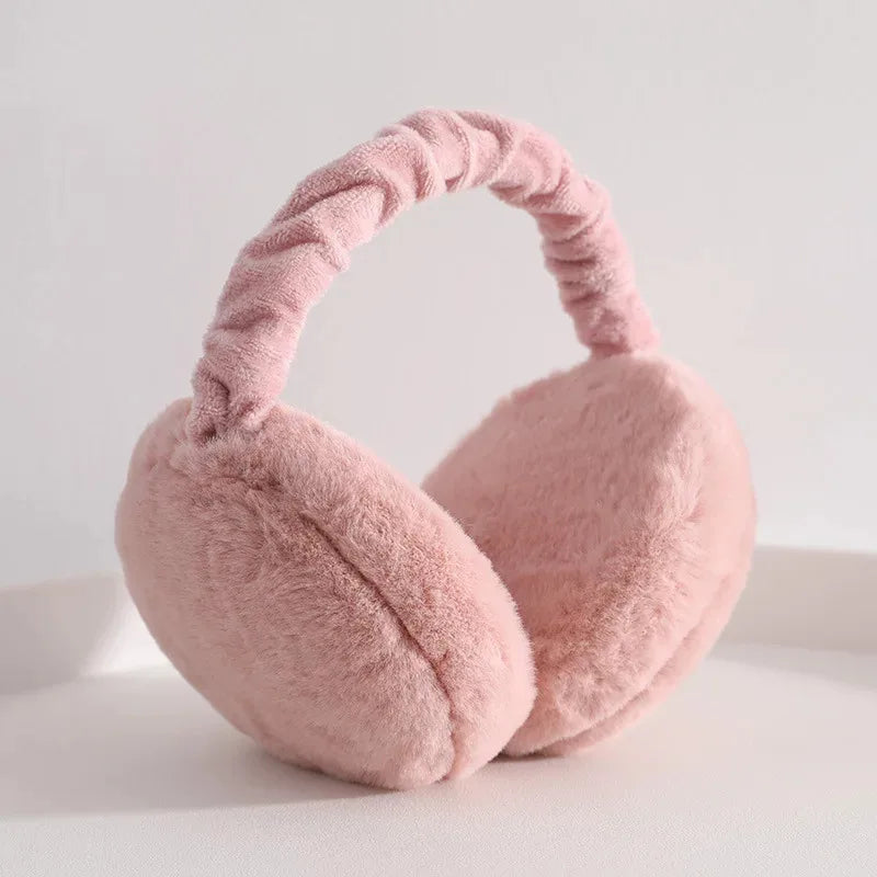 A soft pink plush fur ear warmer with a looped headband is shown against a white background.
