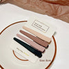 A set of five hand-made vintage frosted geometry hair clips in various shades of pink and brown displayed on a white plate.