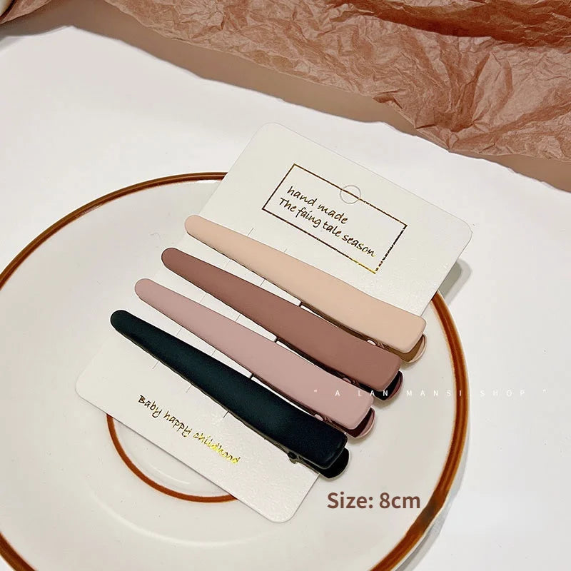 A set of five hand-made vintage frosted geometry hair clips in various shades of pink and brown displayed on a white plate.