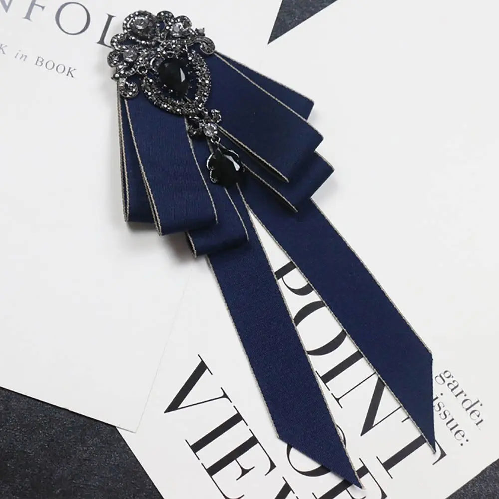 A dark navy blue satin bow tie with a rhinestone embellishment shown against a white background.