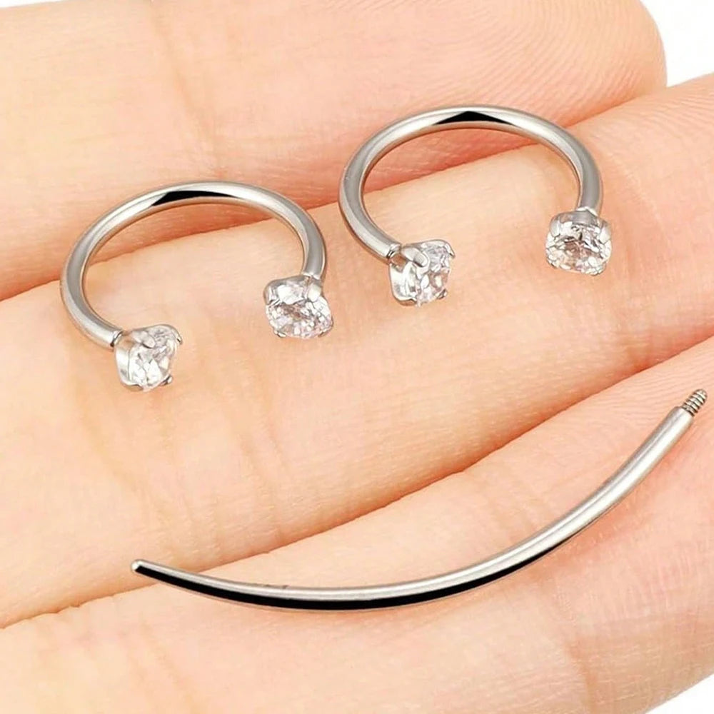 Silver stainless steel horseshoe nose studs with ball grabbers displayed on a hand