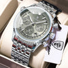 Reloj cronógrafo de pulsera de hombre plateado con brazalete de metal, exhibido en una caja de color claro.