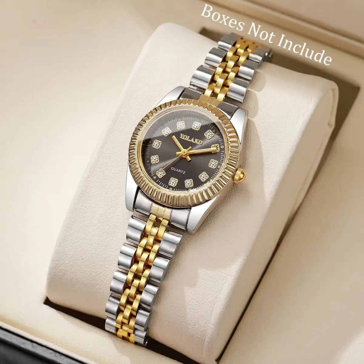 A silver and gold-toned quartz wristwatch with a round face and metal bracelet is displayed on a light-colored box.