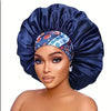 A woman wearing a dark blue satin sleep bonnet with a patterned elastic band