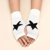 White knitted half finger gloves with a black star pattern worn on a person's hand.