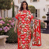 Eine Frau präsentiert ein rotes und orangefarbenes Leopardenmuster-Satin-Abaya-Schalset vor einem weißen Gebäude.