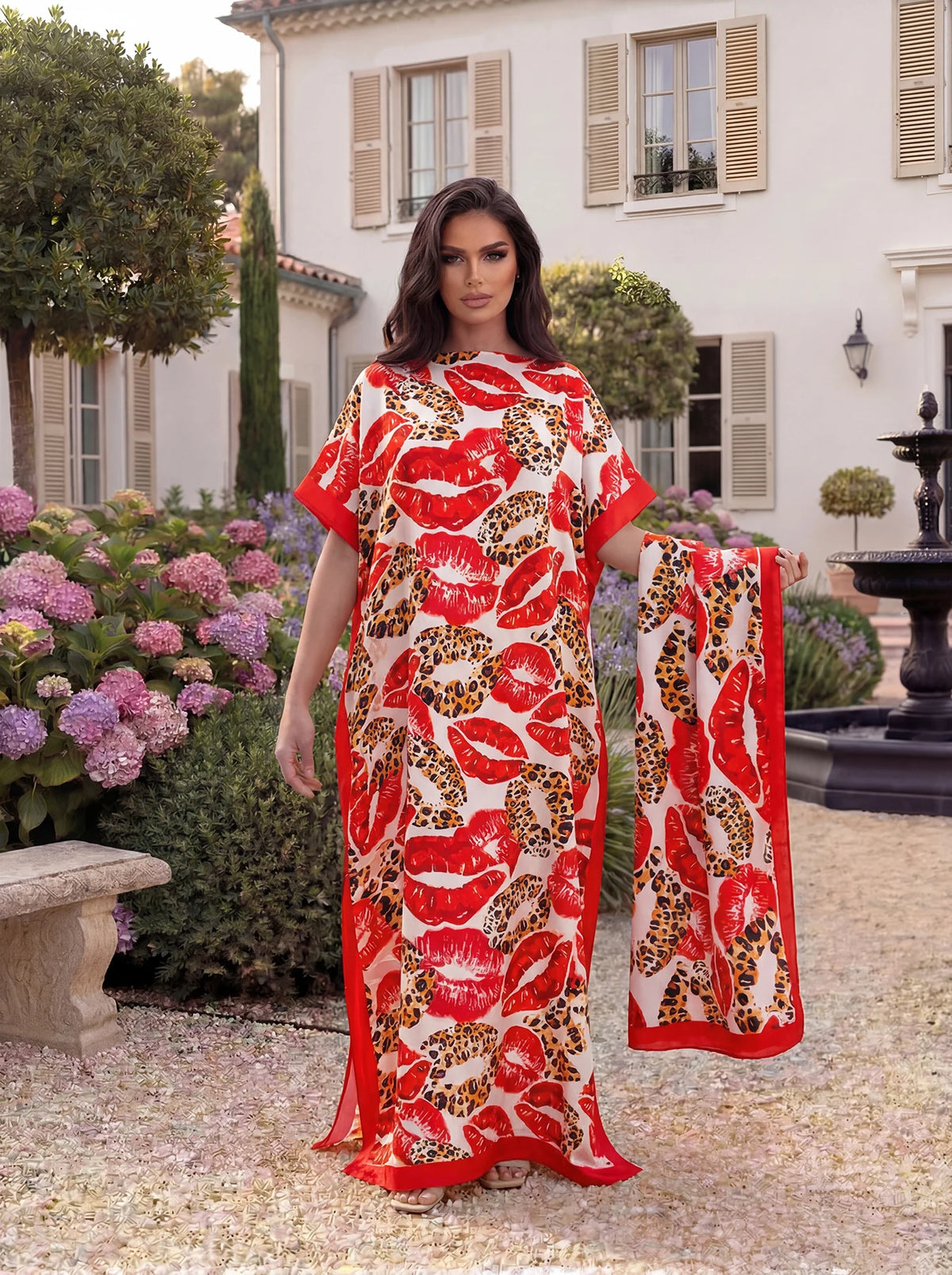 Eine Frau präsentiert ein rotes und orangefarbenes Leopardenmuster-Satin-Abaya-Schalset vor einem weißen Gebäude.