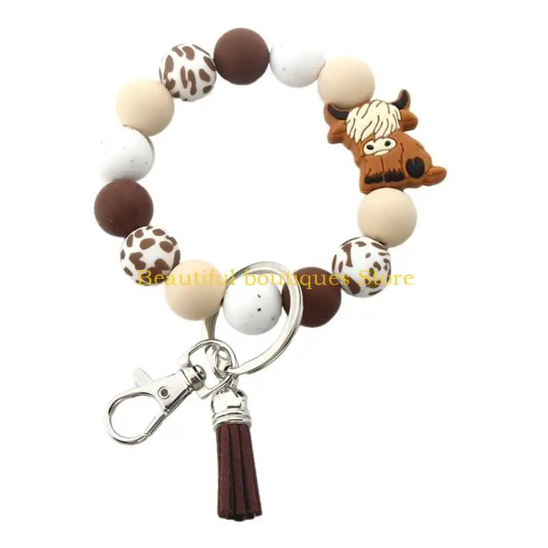 A silicone wristlet keychain featuring various brown and white patterned and solid colored cow-themed beads.